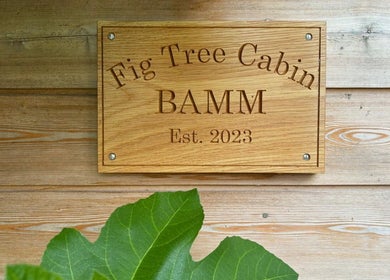 Wooden sign of Fig Tree Cabin at Box, England, GB, showcasing its rustic charm.