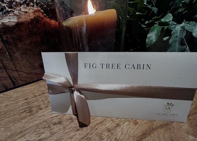 Elegant invitation card with Fig Tree Cabin's logo, Box, England, GB, beside a lit candle.