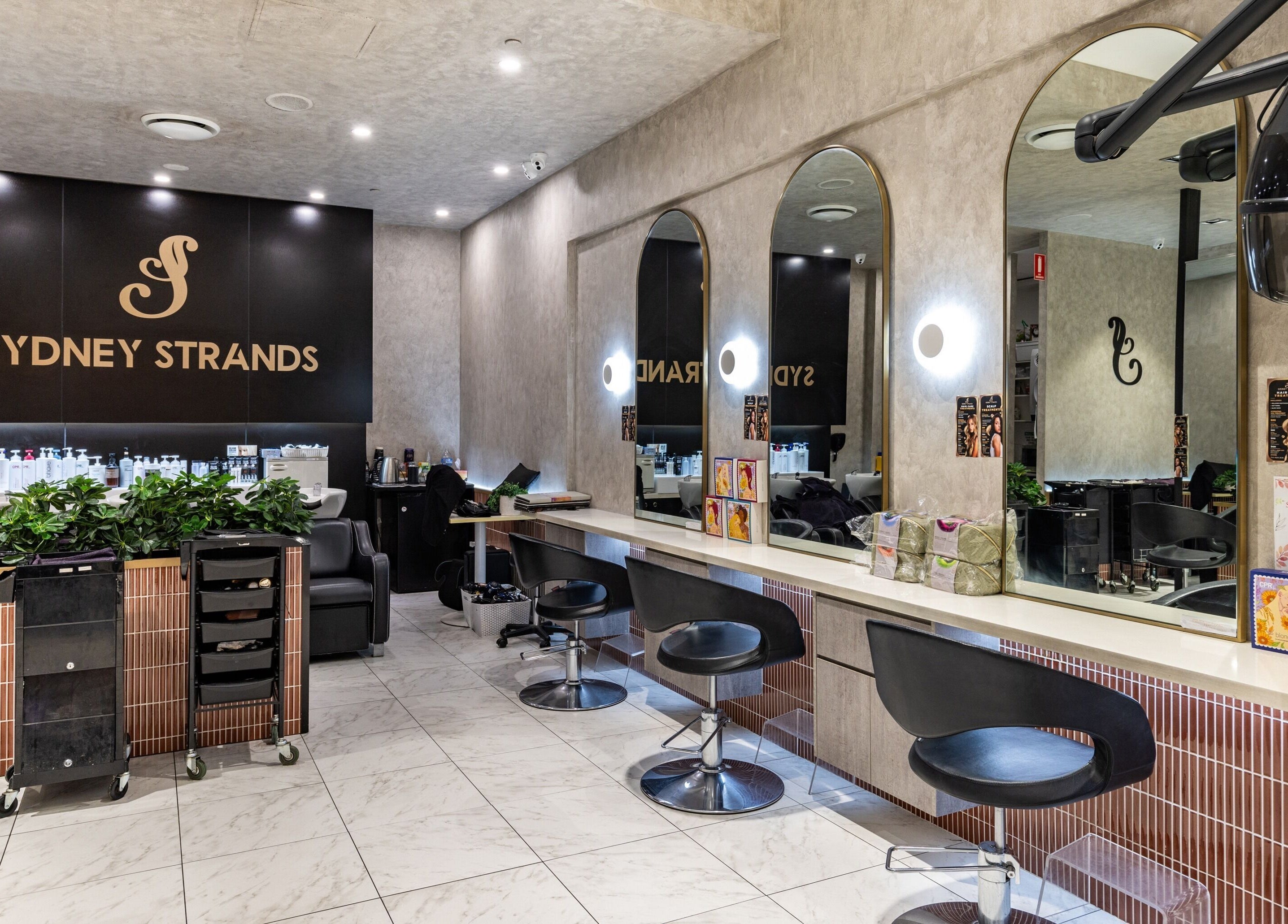 Interior of Sydney Strands salon on Kingsway, Miranda NSW, AU showcasing chic modern seating and mirrors.