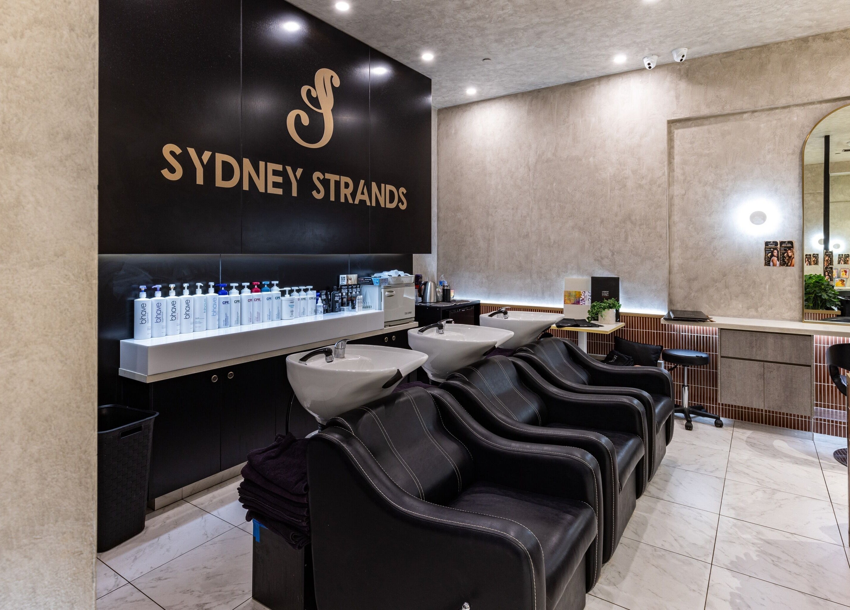 Sydney Strands salon wash area with sleek black chairs at Kingsway, Miranda NSW, AU.