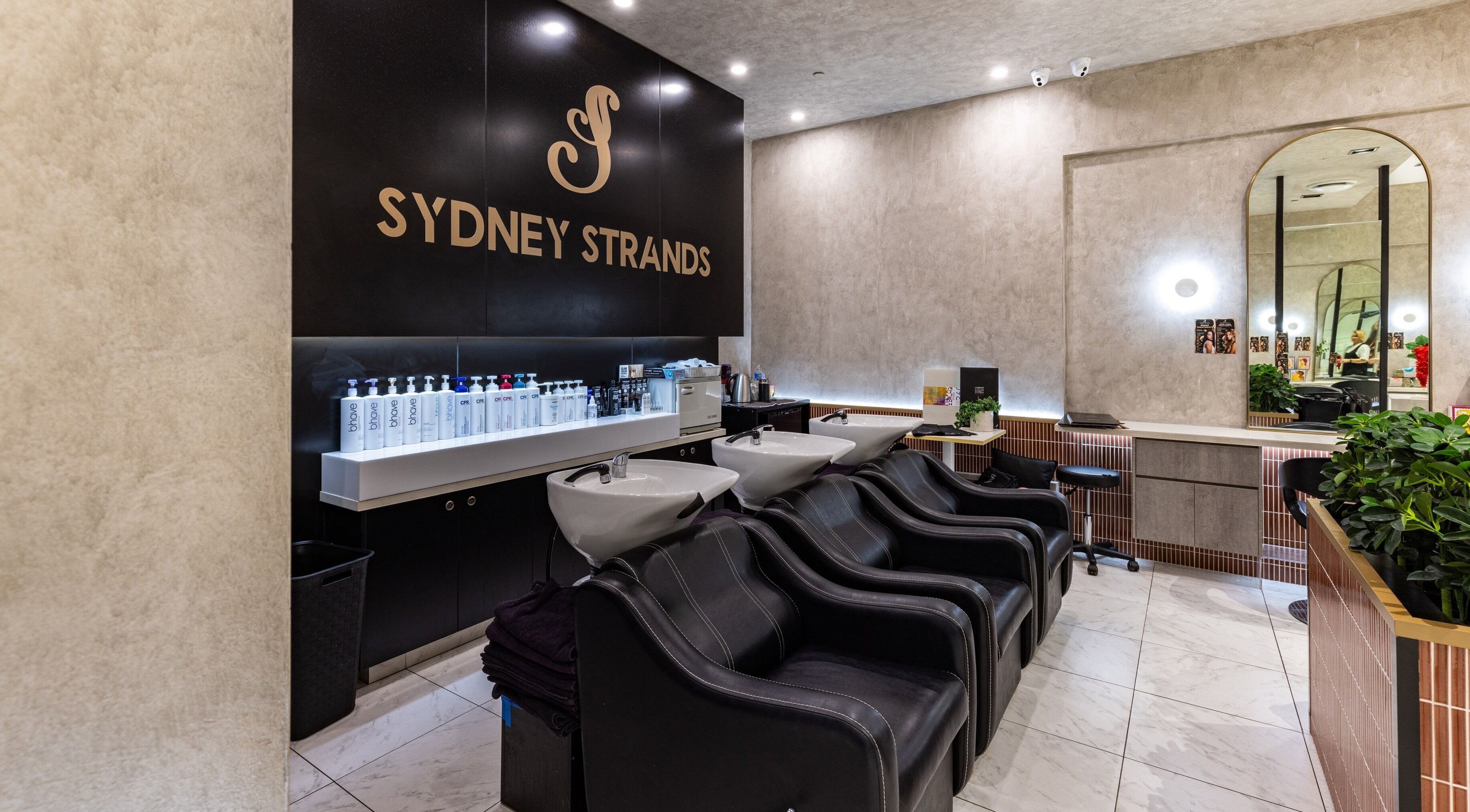 Sydney Strands salon wash area with sleek black chairs at Kingsway, Miranda NSW, AU.