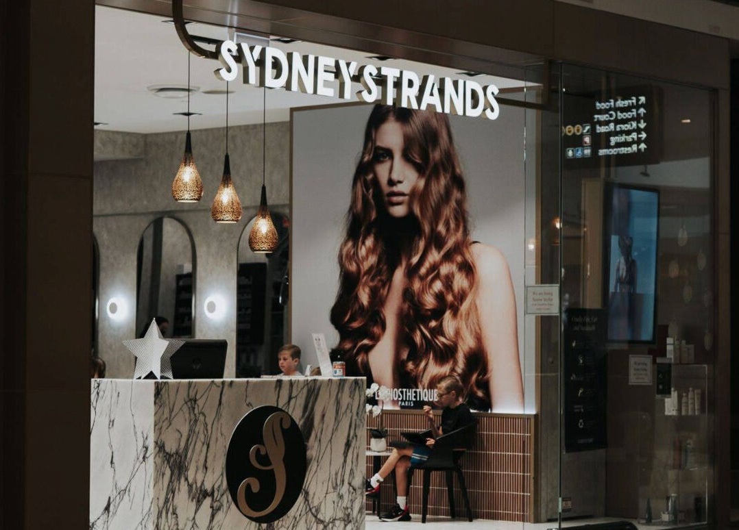 Front view of Sydney Strands salon on Kingsway, Miranda NSW, AU, featuring elegant lighting and decor.