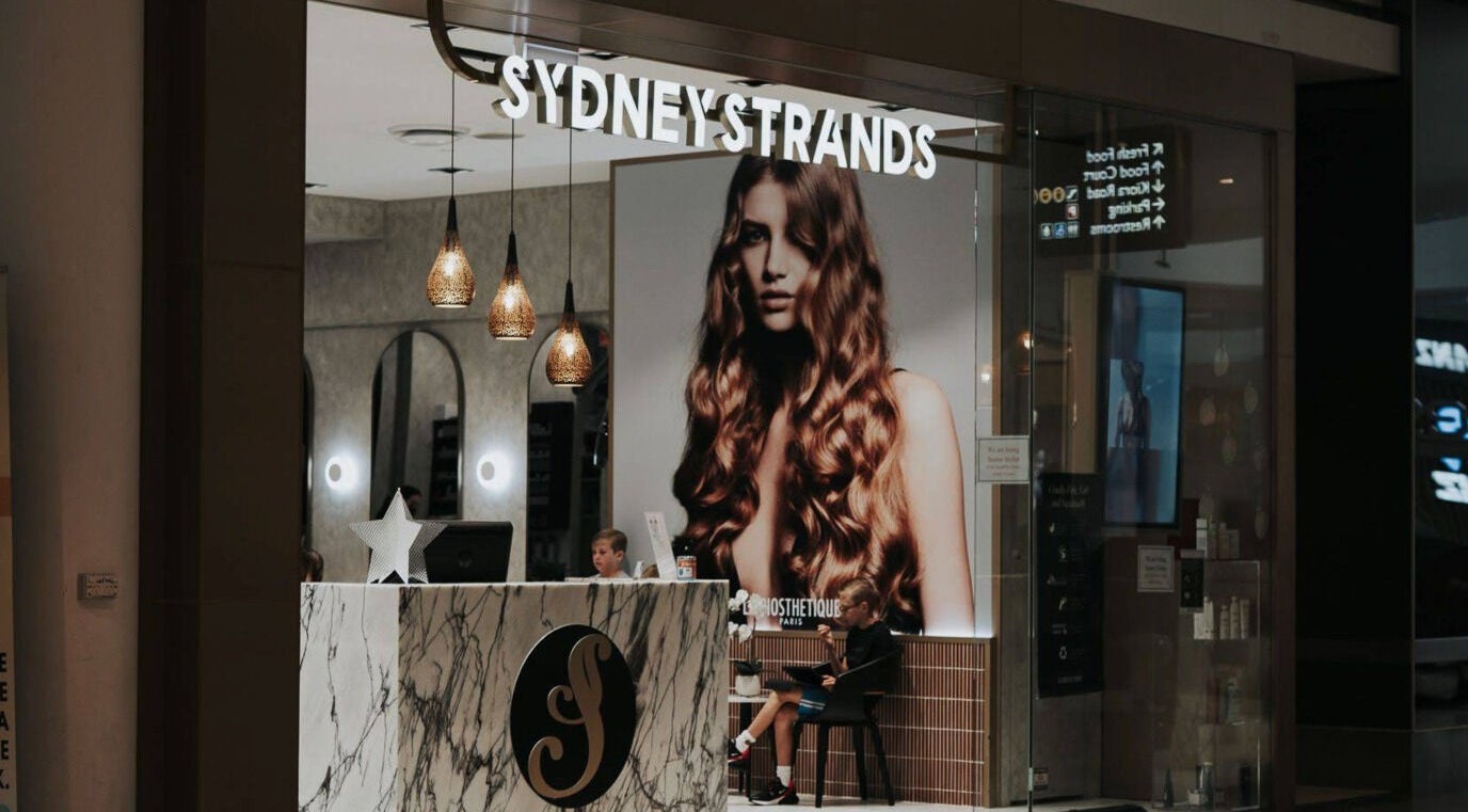 Front view of Sydney Strands salon on Kingsway, Miranda NSW, AU, featuring elegant lighting and decor.