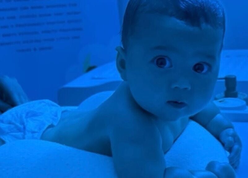 Baby enjoys massage at Daydreams Infant Massage in Dianella, Western Australia, AU under soothing blue lighting.