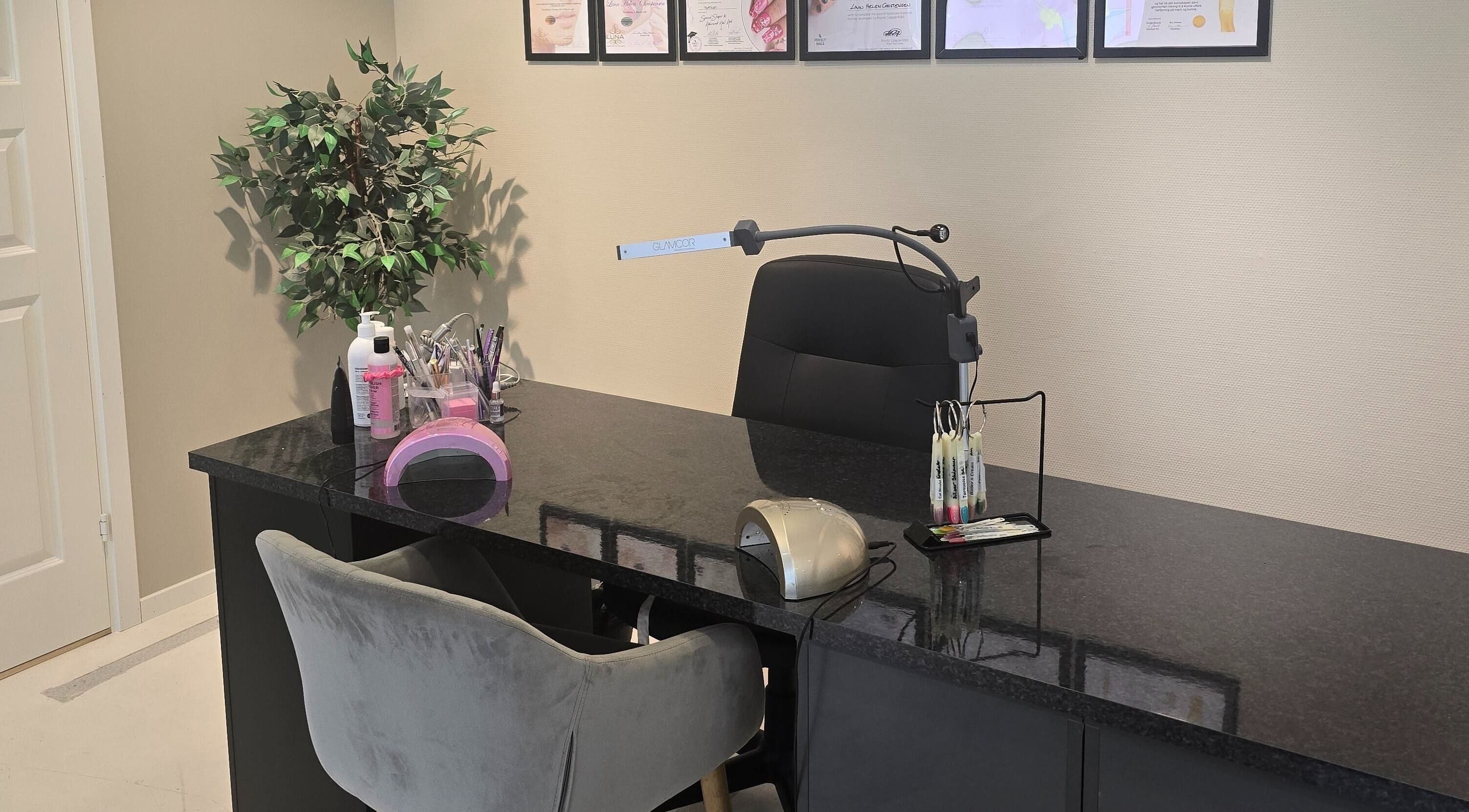 XO Beauty & Academy AS i Sarpsborg, Østfold, elegant neglebord med sertifikater på veggen.