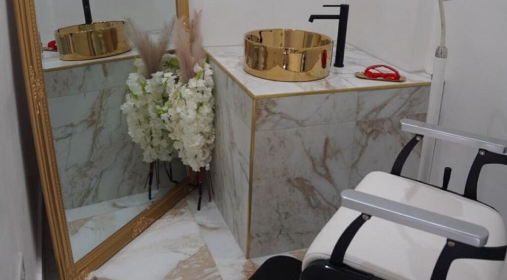 Luxurious vanity area at Athena Mortlake, London, England, GB with gold sink and marble tiles.
