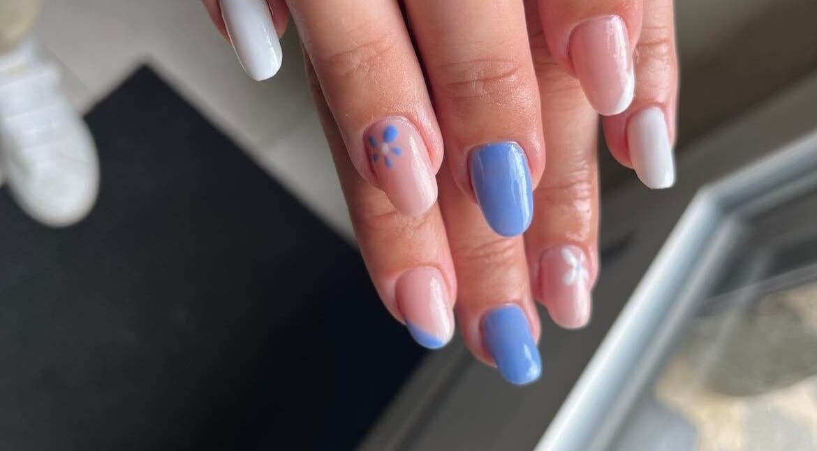 Une manucure pastel à Les Douces Heures De Marie, Ruffiac, Bretagne, FR avec des motifs floraux blancs et bleus.