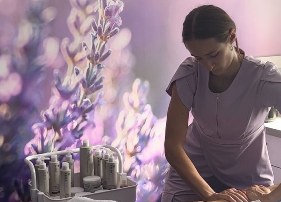 Massage therapist at Living Well with Milly, Hereford, England, GB, in a calming lavender-themed room.