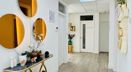 Elegant hallway at Mraya Clinic, Northwood, England, GB, featuring gold mirrors and warm lighting.