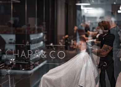 Stylish barber working at Chaps & Co Yas Mall, Abu Dhabi, AE. Sleek interior and professional service.
