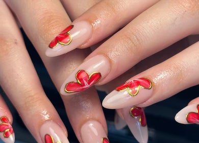 Close-up of floral nail art at Beauty By Phoebs, Reigate, England, GB showcasing red and gold design.