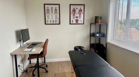 Modern therapy room at Resolve Massage, Bournemouth, England, GB with massage table and anatomical posters.