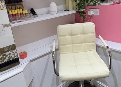 Comfortable makeup chair in Victoria Jane Makeup, Glasgow, Scotland, GB with beauty products on shelf.