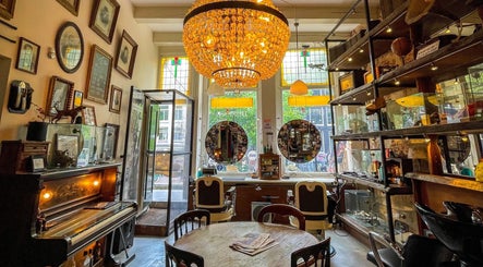 Cozy vintage interior of Cutting Casper in Amsterdam, Noord-Holland, NL, featuring a chandelier and antique decor.