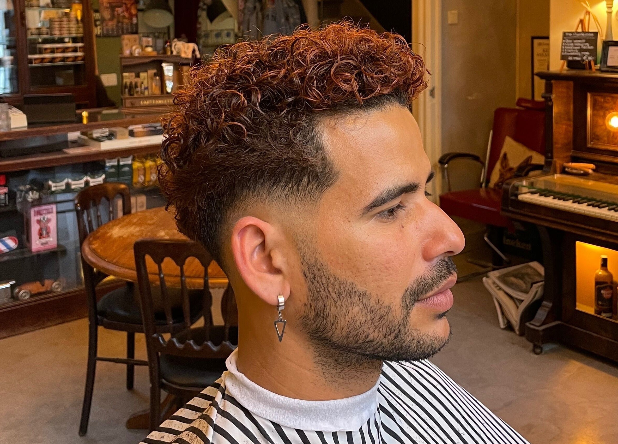 Man with curly haircut at Cutting Casper, Amsterdam, Noord-Holland, NL in a chic barber setting.