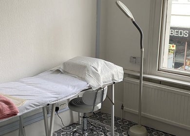 Relaxing treatment room at iBeautify Royal Tunbridge Wells, England, GB with cozy bed and lamp.