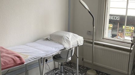 Relaxing treatment room at iBeautify Royal Tunbridge Wells, England, GB with cozy bed and lamp.