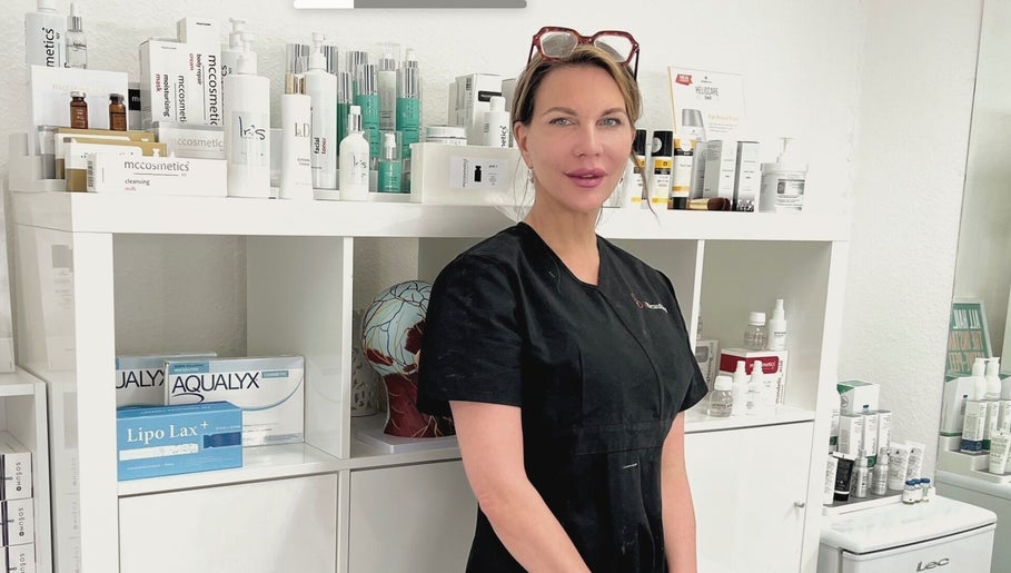 Beauty professional at iBeautify, Royal Tunbridge Wells, GB, with skincare products in the background.