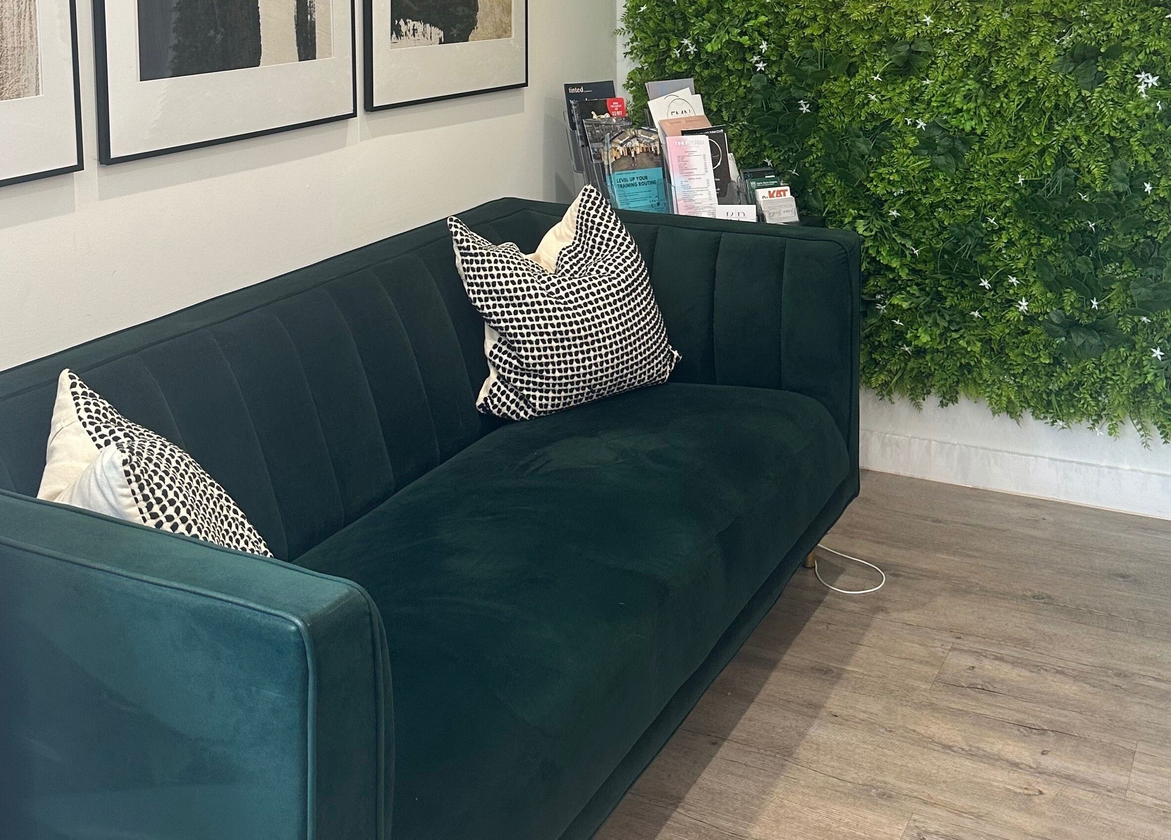 Stylish seating area at Dolled Up by Alex, Hadleigh, England, GB, with lush green decor and modern sofa.