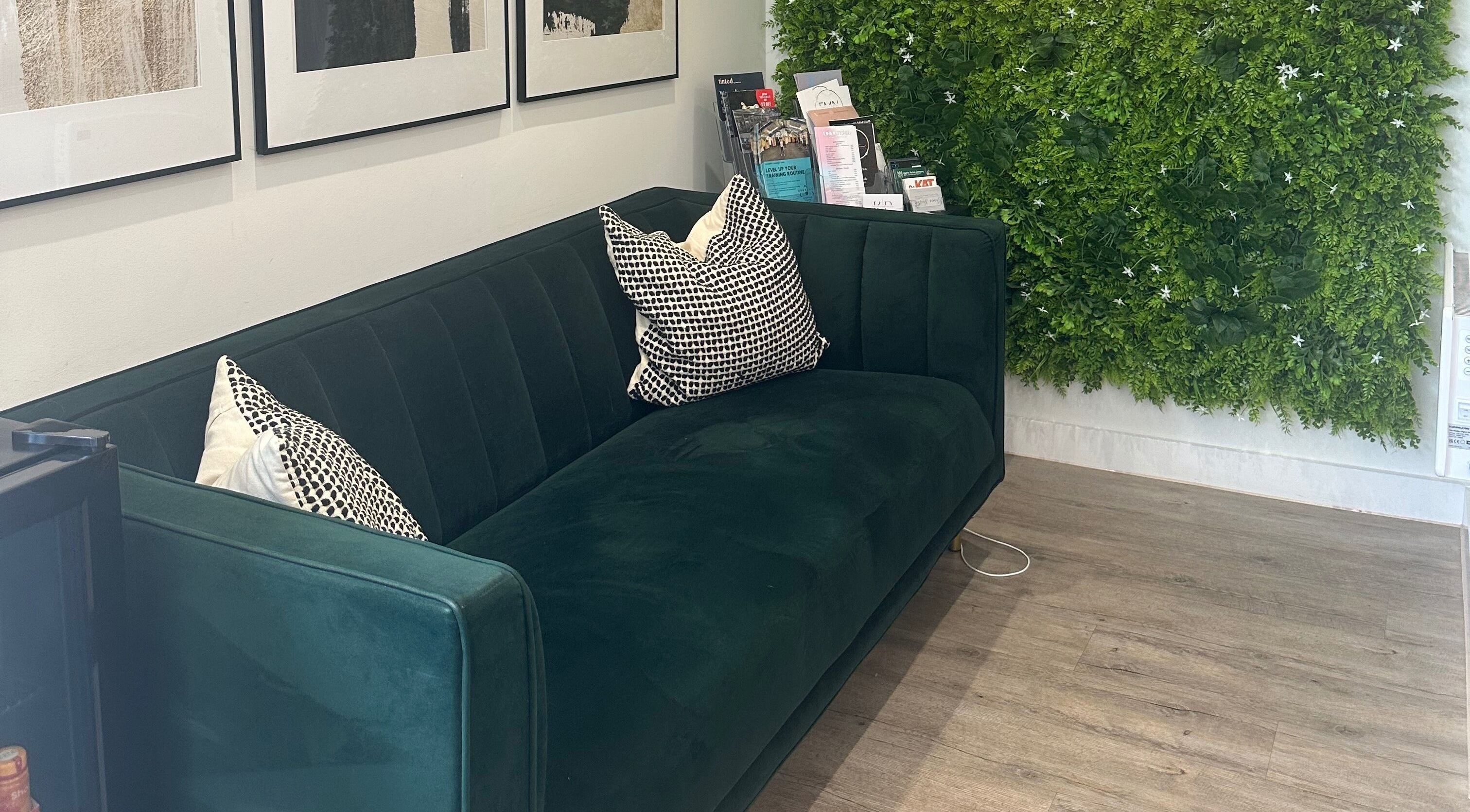 Stylish seating area at Dolled Up by Alex, Hadleigh, England, GB, with lush green decor and modern sofa.