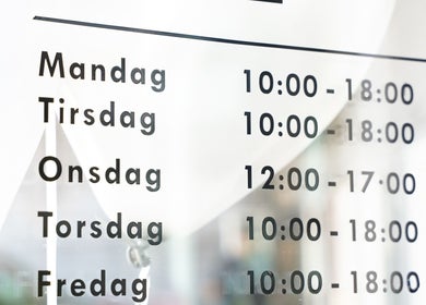 Dogan Barbershop operating hours displayed on a window in Stavanger, Rogaland, NO.
