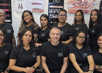 Équipe de Mynails Spa LTD à Port Louis, Port Louis District, MU, souriant devant des présentoirs de vernis.