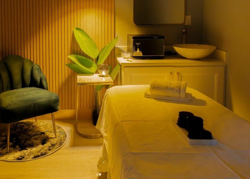 Relaxing spa treatment room at In The Cloud Spa, Toronto, Ontario, CA with a plush chair and massage table.