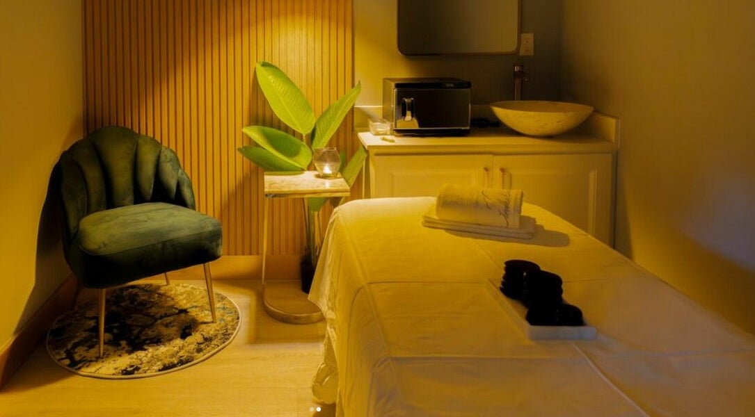 Relaxing spa treatment room at In The Cloud Spa, Toronto, Ontario, CA with a plush chair and massage table.