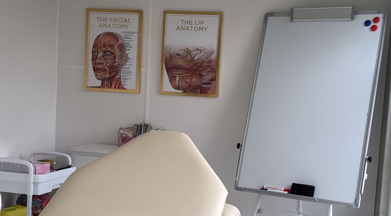 Aesthetics By Lish in Worcester, England. Room features anatomical posters and a whiteboard for learning.