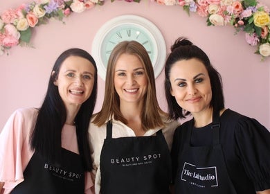 Three smiling beauticians at Beauty Spot Salon, Port Elizabeth, Eastern Cape, ZA, with floral decor.