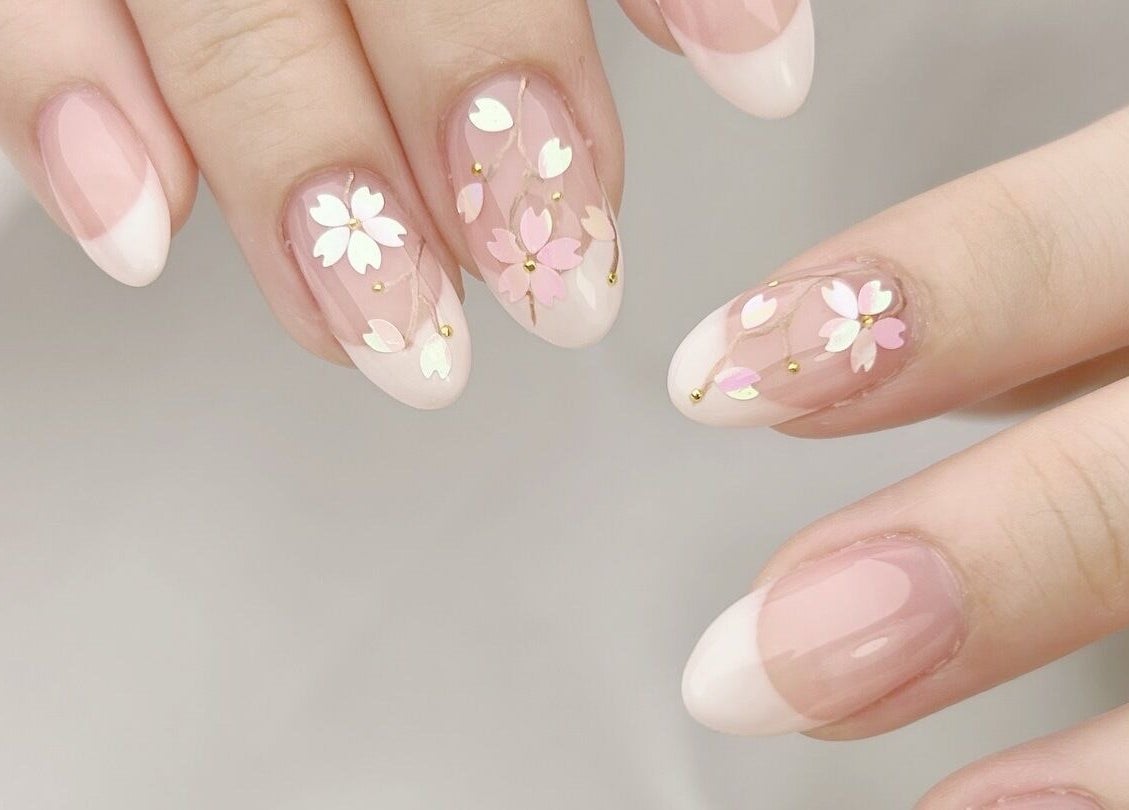 Floral nail art by Nail Room at 香港島, 香港島, HK features delicate white and pink flowers with gold accents.