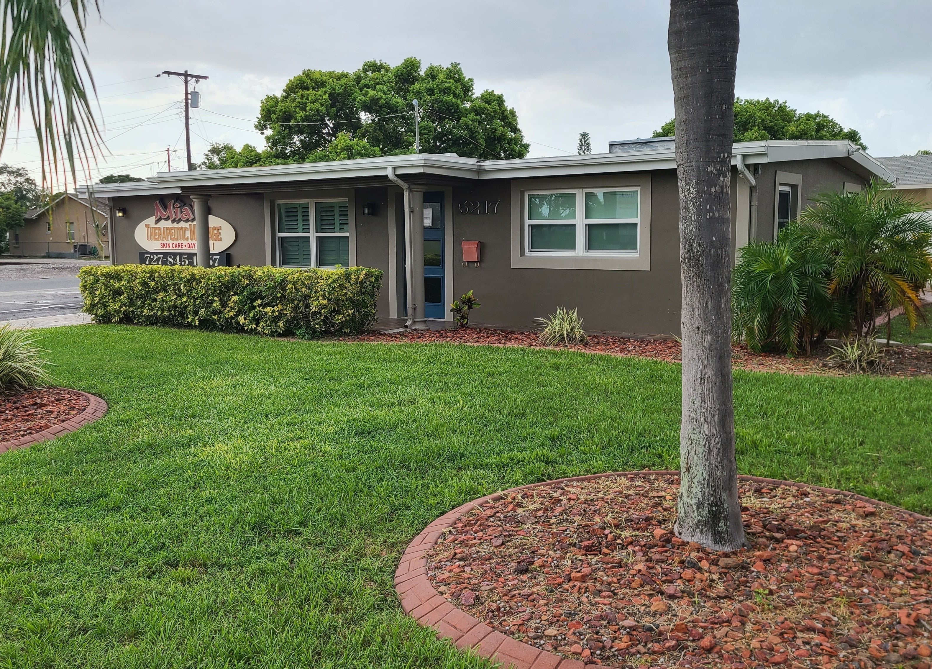 Exterior view of The Muscle Whisperer in New Port Richey, Florida with lush greenery.