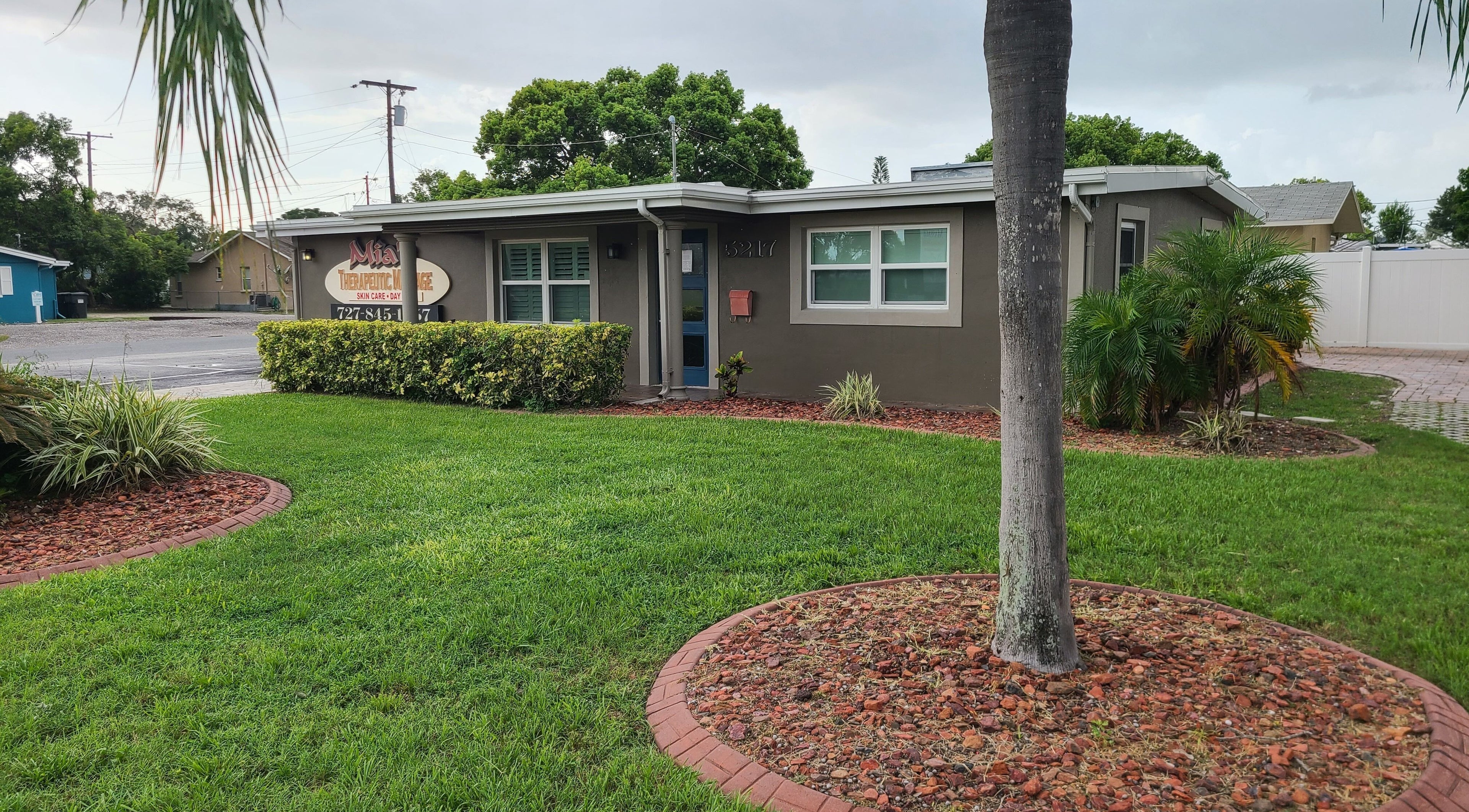 Exterior view of The Muscle Whisperer in New Port Richey, Florida with lush greenery.