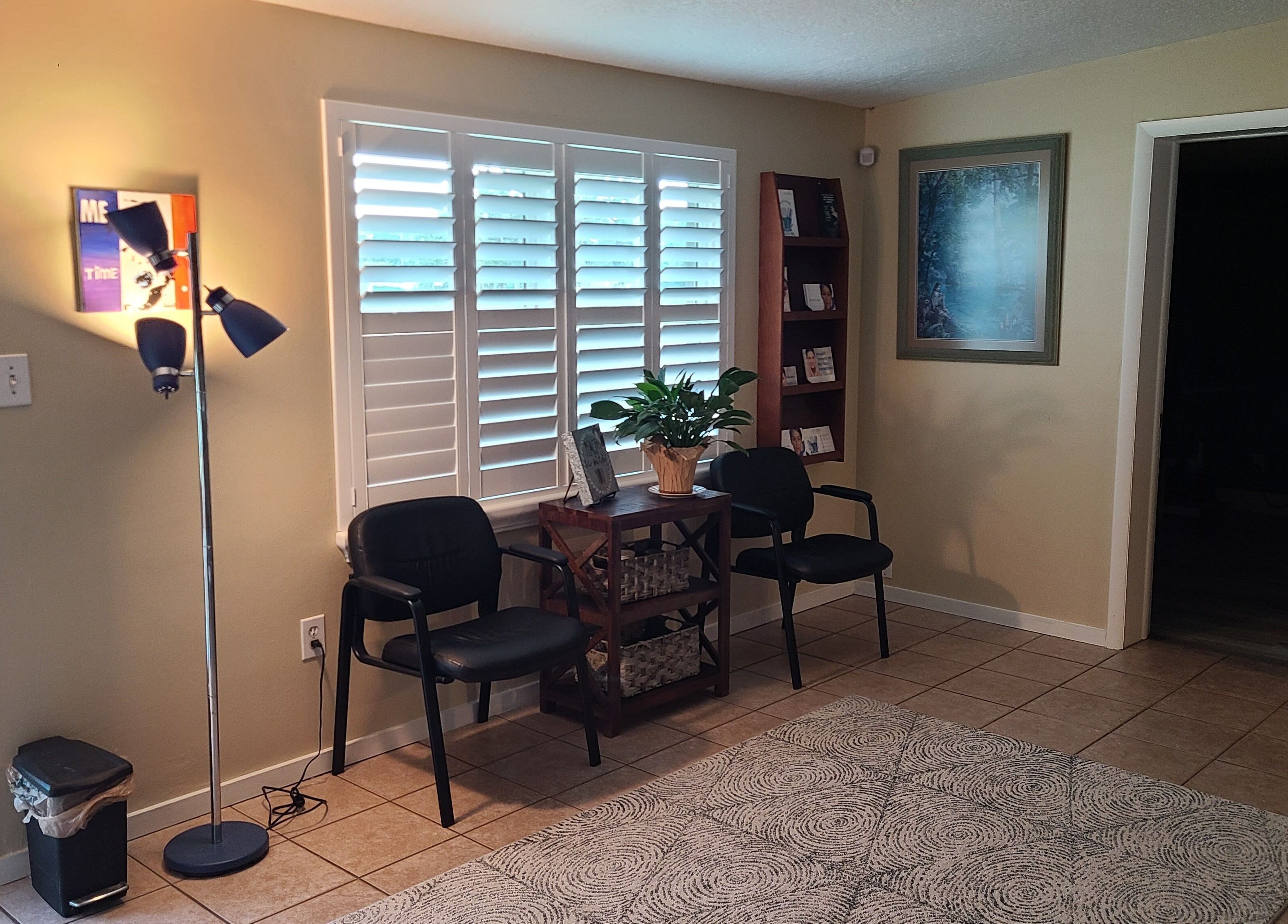 Inviting waiting area at The Muscle Whisperer in New Port Richey, Florida, US with chairs, a lamp, and decor.