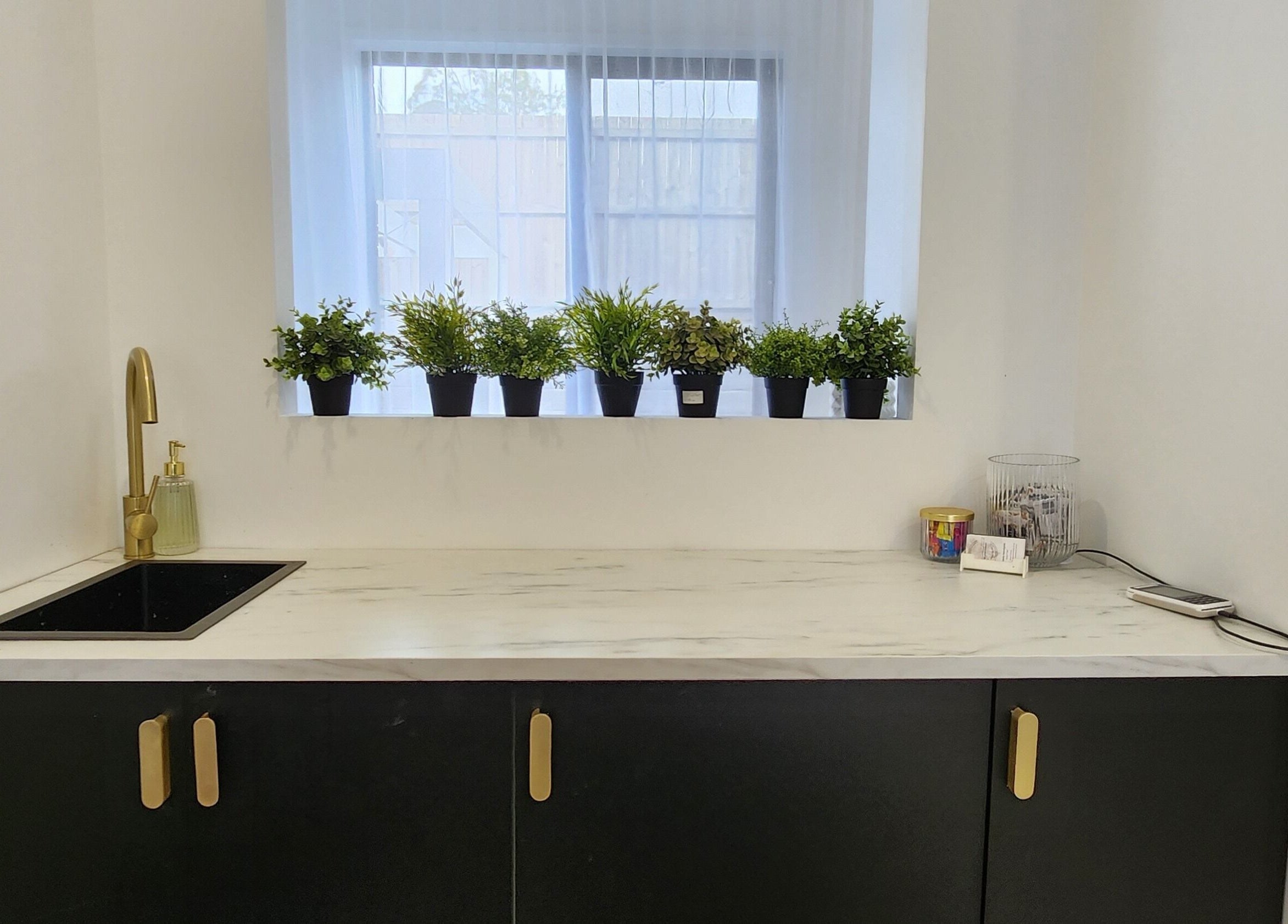Stylish sink area at AimeeLea Hairdressing, Cornubia, Queensland, AU with plants and gold faucet.