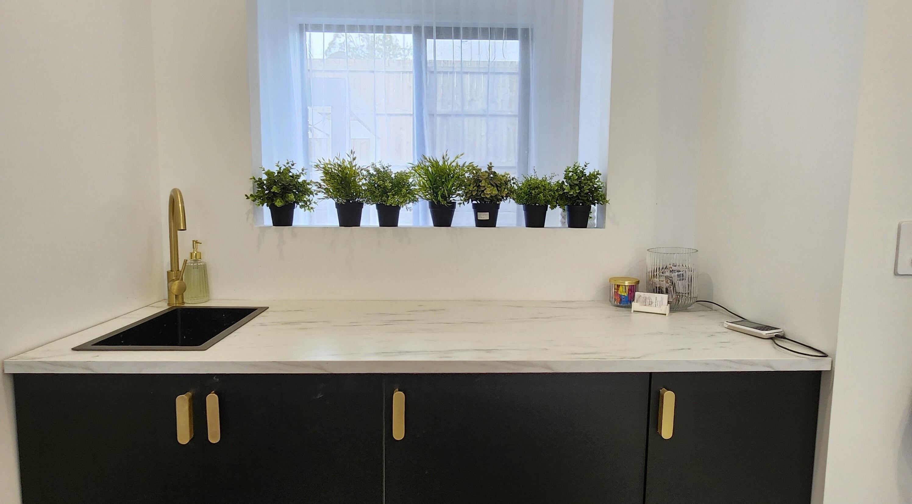 Stylish sink area at AimeeLea Hairdressing, Cornubia, Queensland, AU with plants and gold faucet.