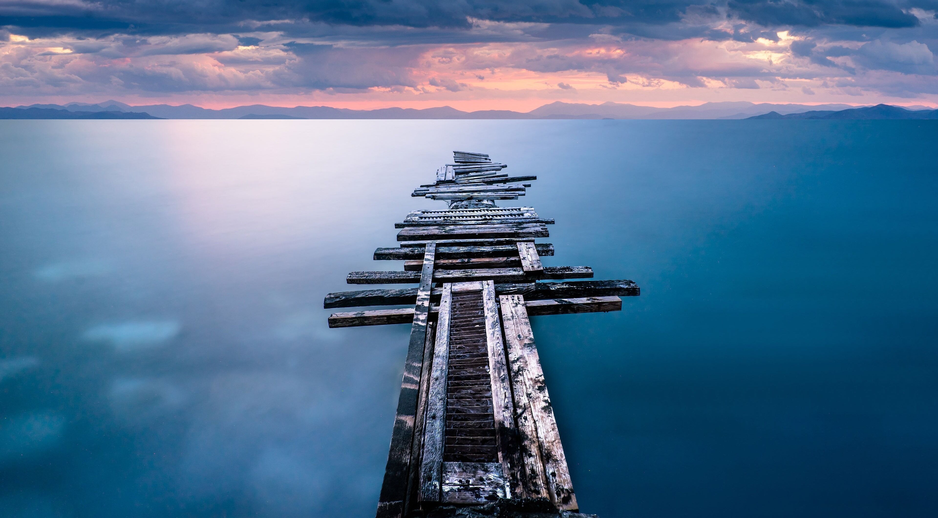 Rustic wooden pier extending into a tranquil sea at sunset near TEAspot: GA, Macon, Georgia, US.