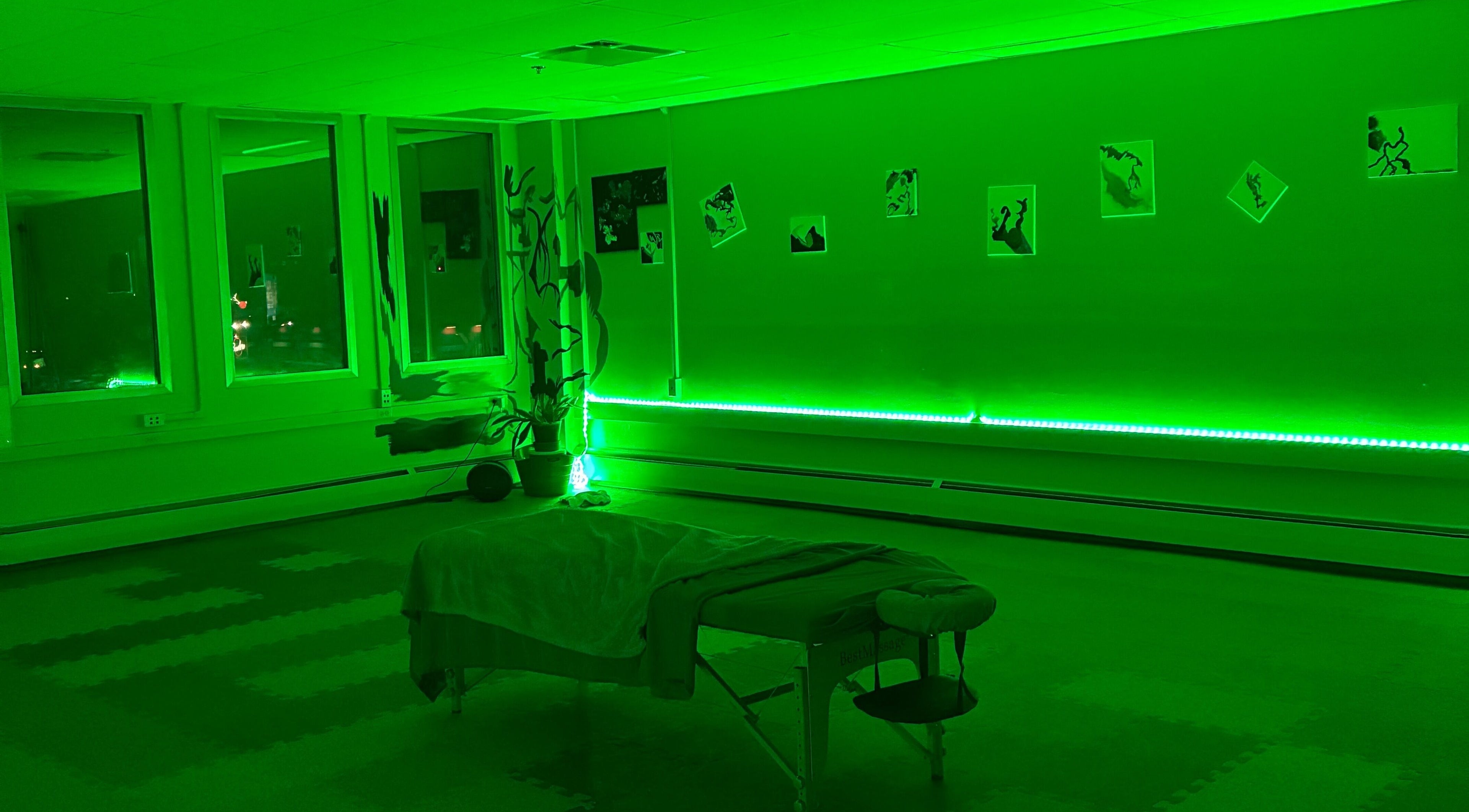 Relaxing green-lit therapy room at TEAspot: Denver Pilates on the Move in Denver, Colorado, US with massage table.