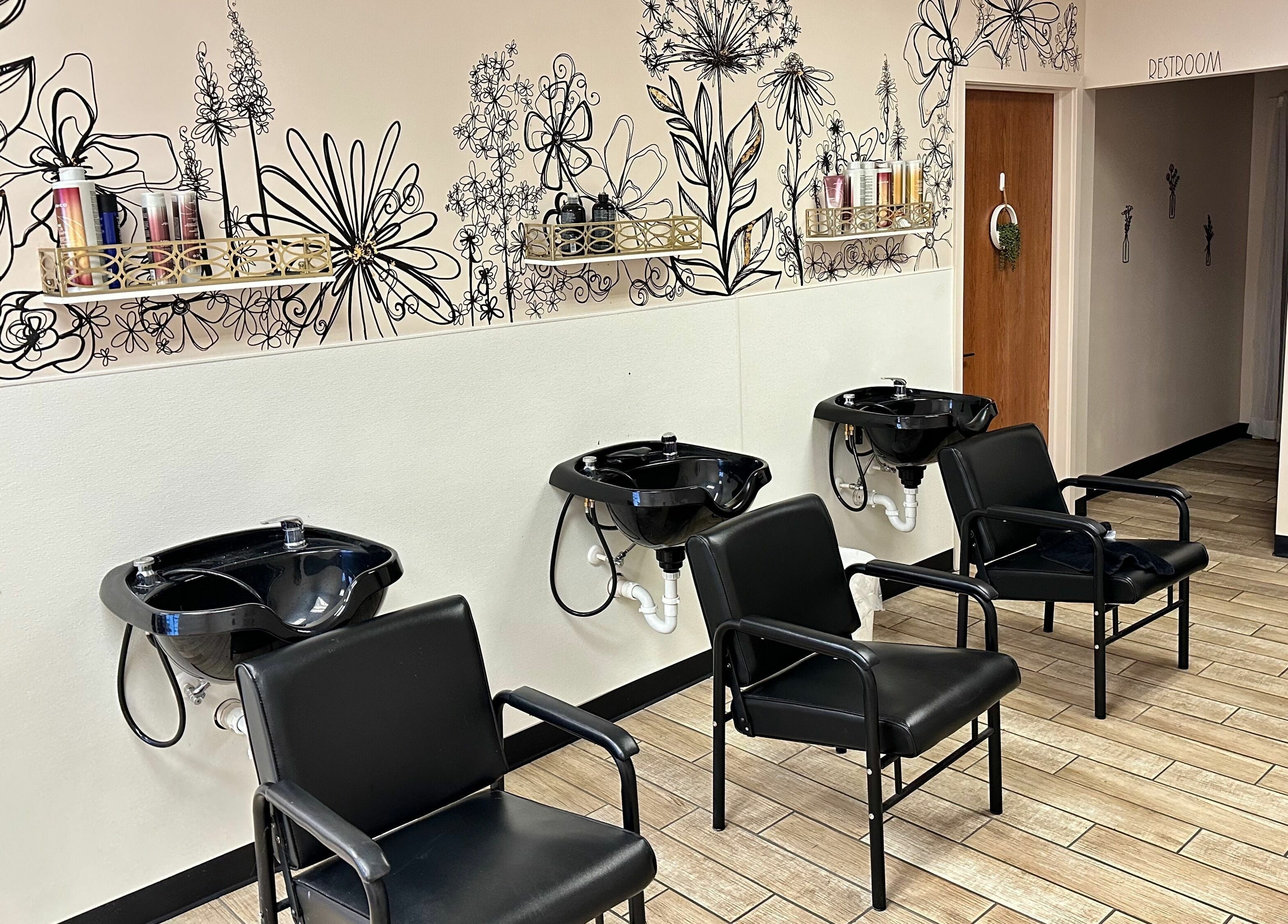 Elegant wash stations at Urban Allure Salon and Studios in Roy, Utah, US with floral wall art and sleek chairs.