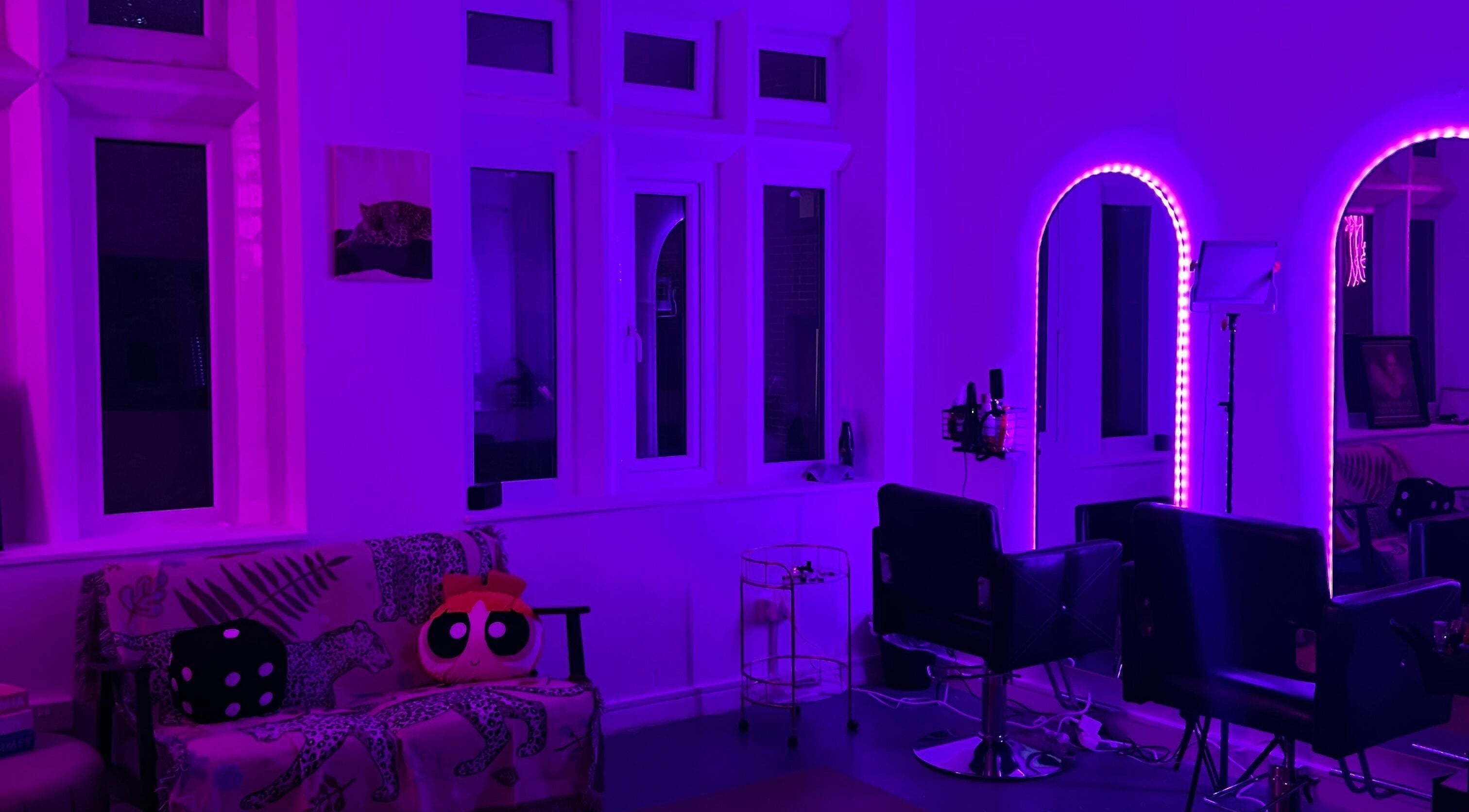 Vibrant purple lit salon interior at Angel Lashes, Newcastle upon Tyne, featuring chic chairs and wall accents.