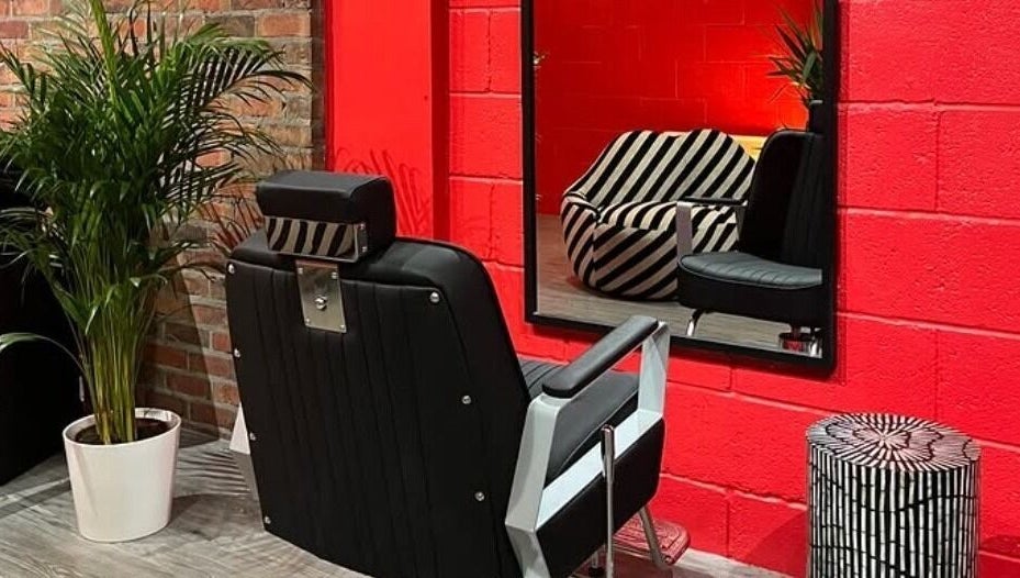 Cult.Collective's chic salon in Bristol, England, GB. Bold red walls, modern chairs, and green plants create a stylish atmosphere.