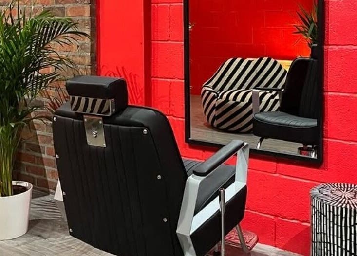 Cult.Collective's chic salon in Bristol, England, GB. Bold red walls, modern chairs, and green plants create a stylish atmosphere.