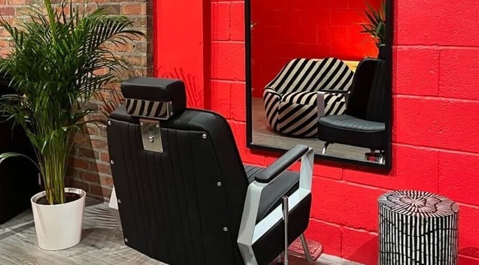 Cult.Collective's chic salon in Bristol, England, GB. Bold red walls, modern chairs, and green plants create a stylish atmosphere.