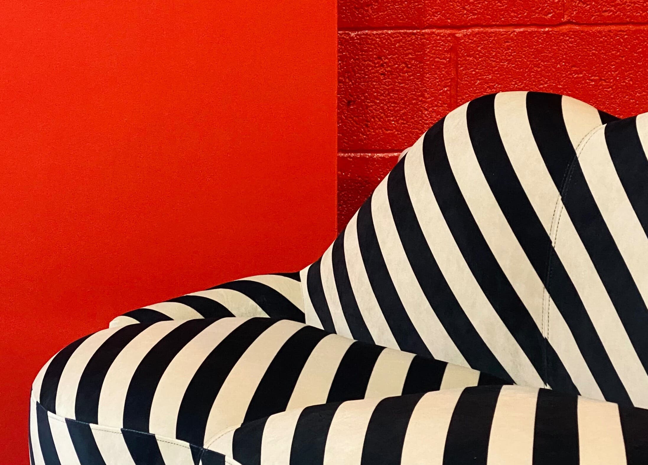 Black and white striped sofa at Cult.Collective, Bristol, England, GB with bold red wall background.