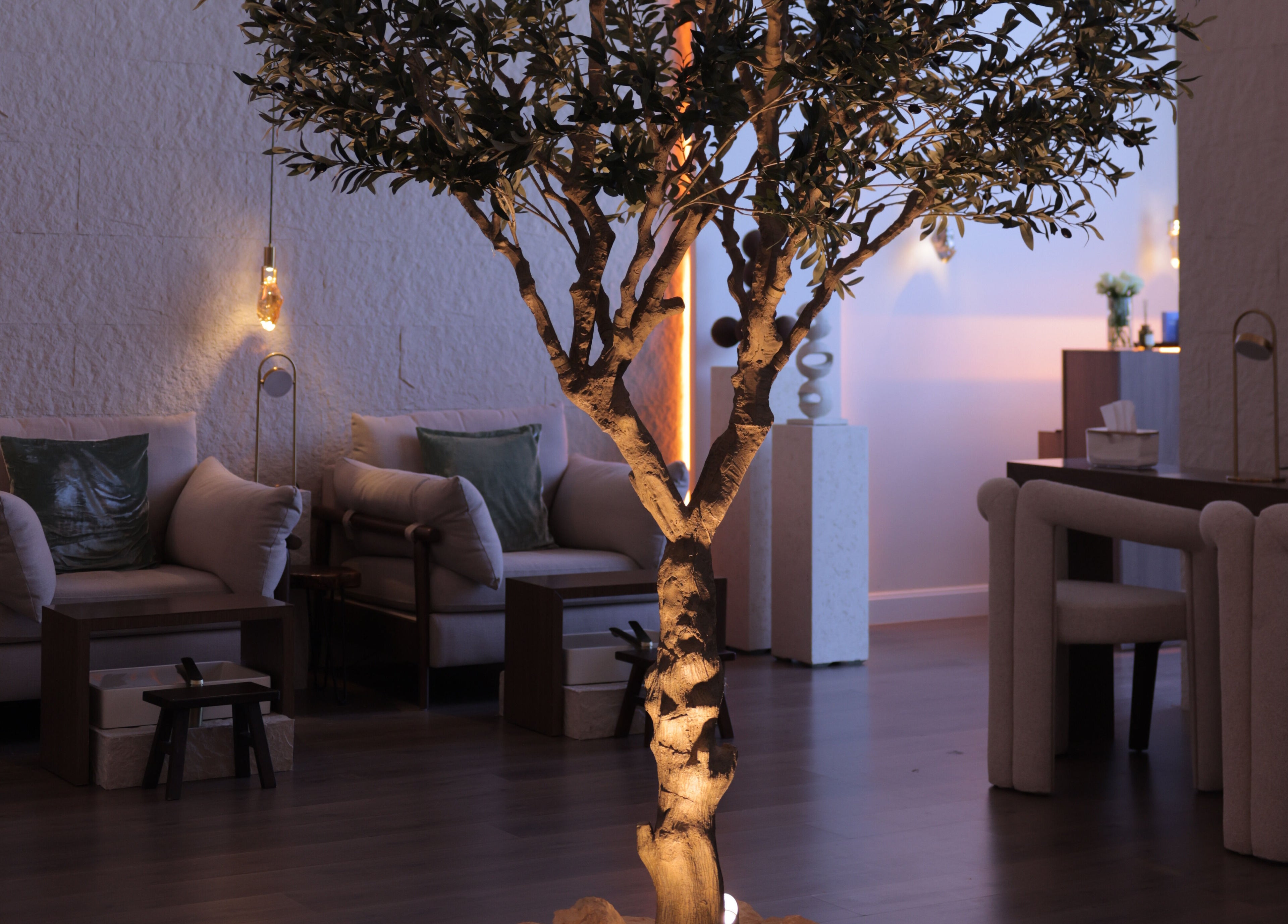 Serene seating area at Calm Spa, Riyadh, featuring a softly lit tree and cozy chairs for relaxation.