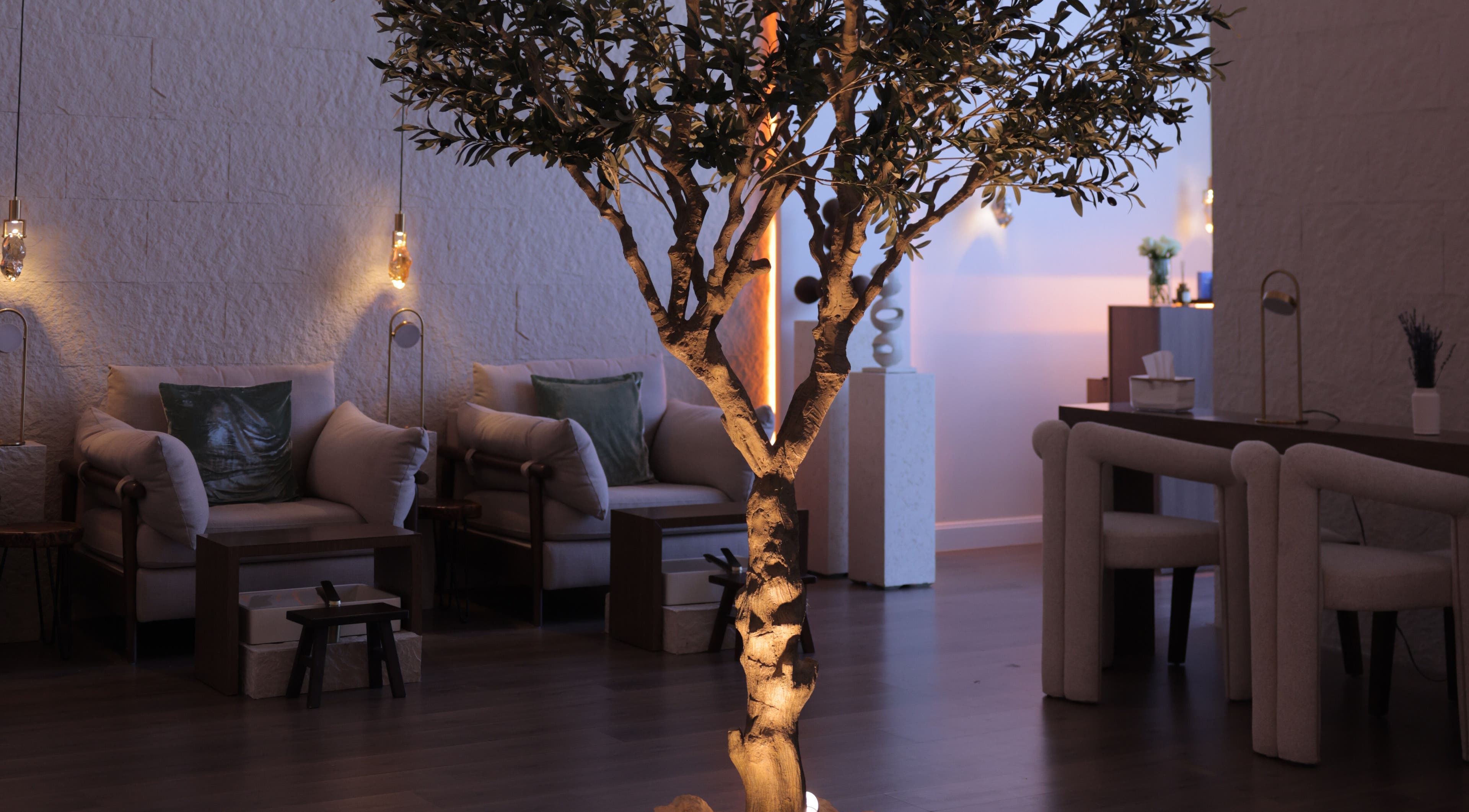 Serene seating area at Calm Spa, Riyadh, featuring a softly lit tree and cozy chairs for relaxation.