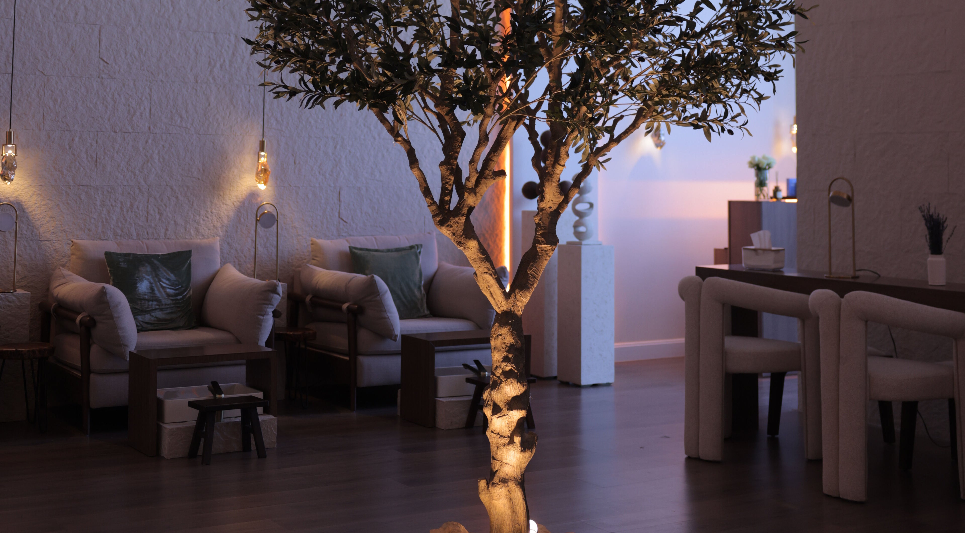 Serene seating area at Calm Spa, Riyadh, featuring a softly lit tree and cozy chairs for relaxation.