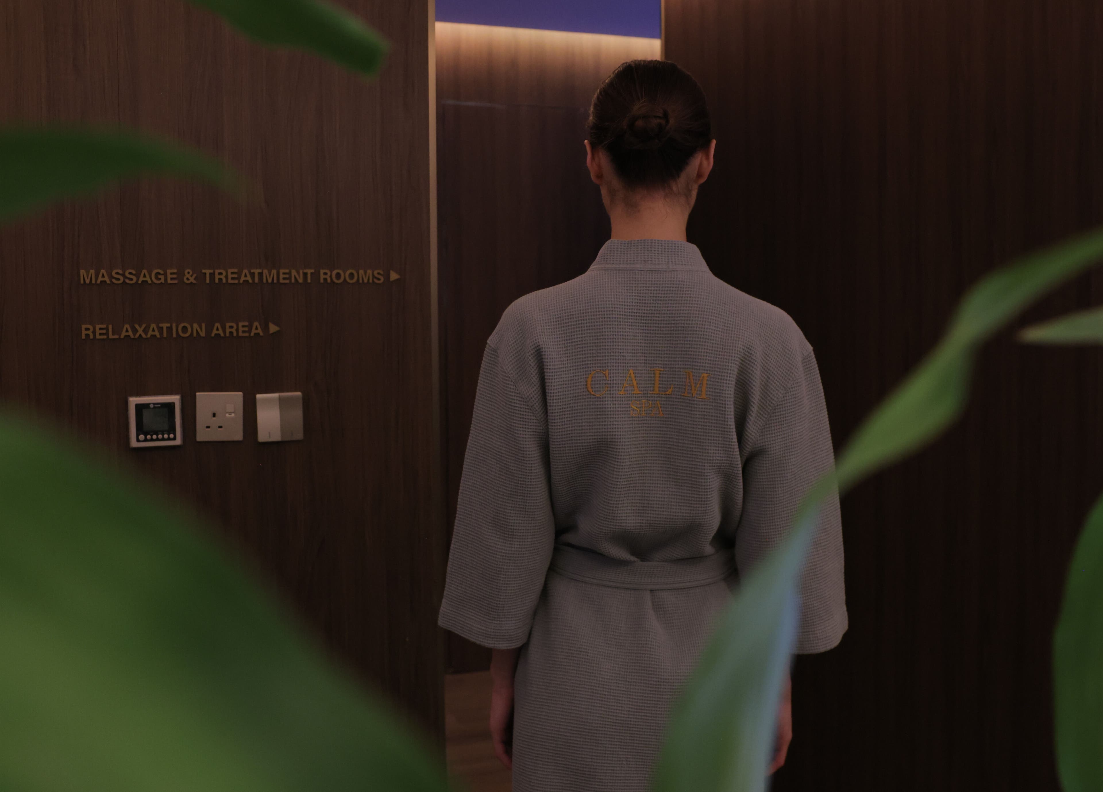 A guest in robe enters Calm Spa, Riyadh, finding tranquility in the massage and relaxation area.