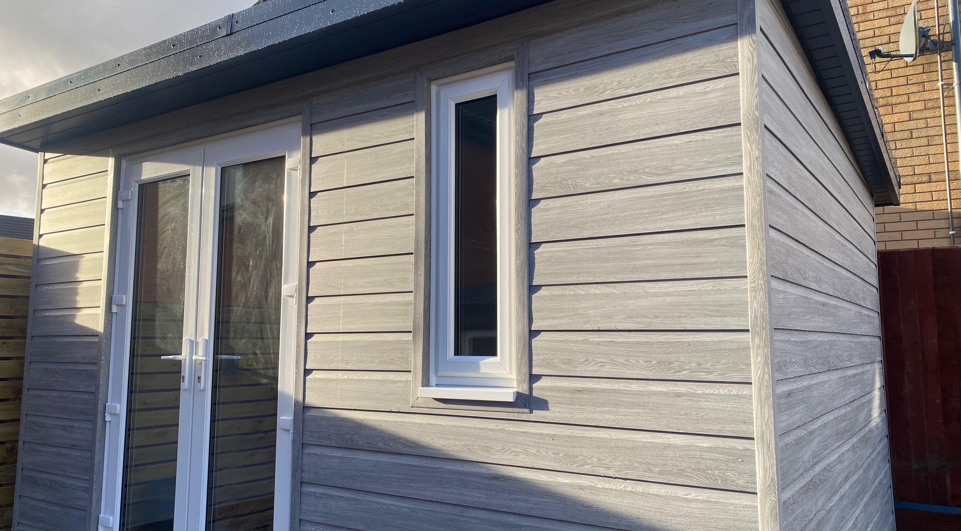 Exterior of Nailsbysadie, a stylish wooden venue in Merthyr Tydfil, Wales, GB, with modern white doors.