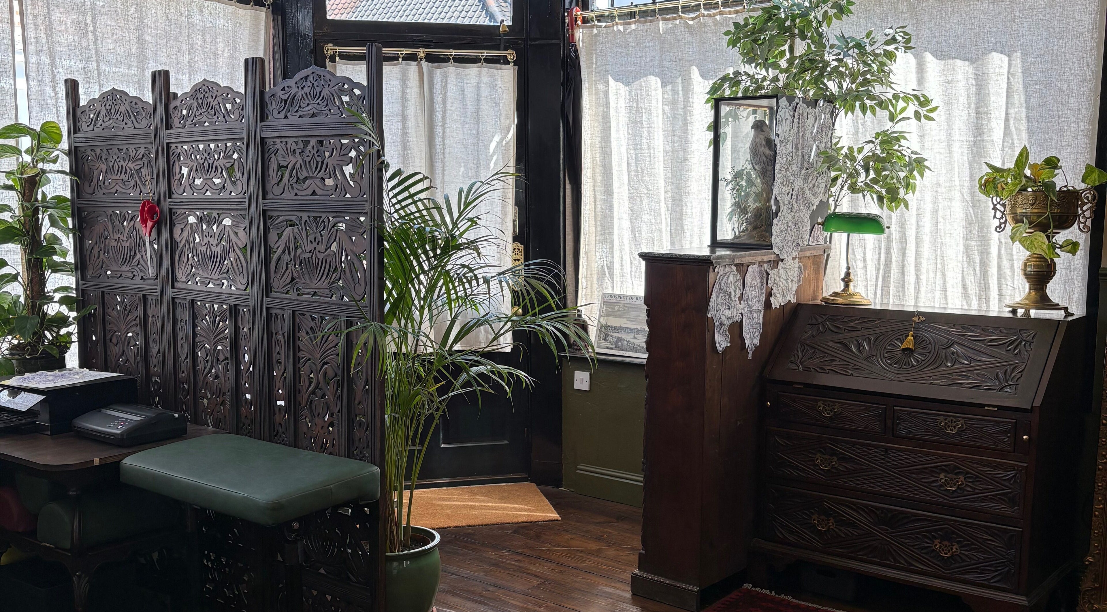 Elegant interior of Lacey Law Studio ‘The Eyrie’ in Norwich, England with antique furniture and lush plants.